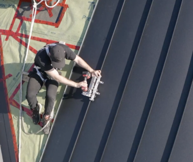 Steel roofing vs metal roofing. Worker fastens steel roof.